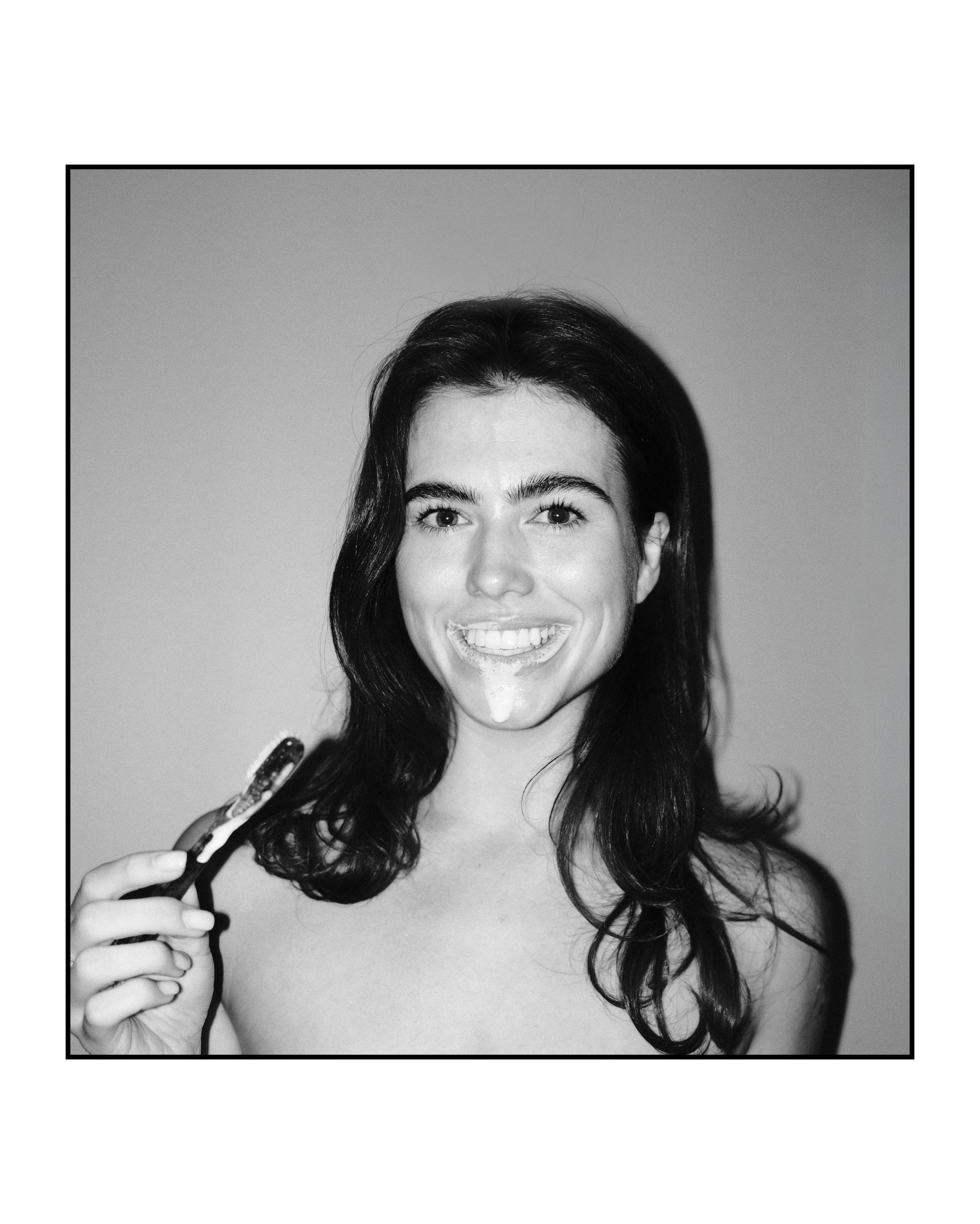 Woman smiling with Natuoral natural toothbrush and fluoride-free hydroxyapatite toothpaste - travel set